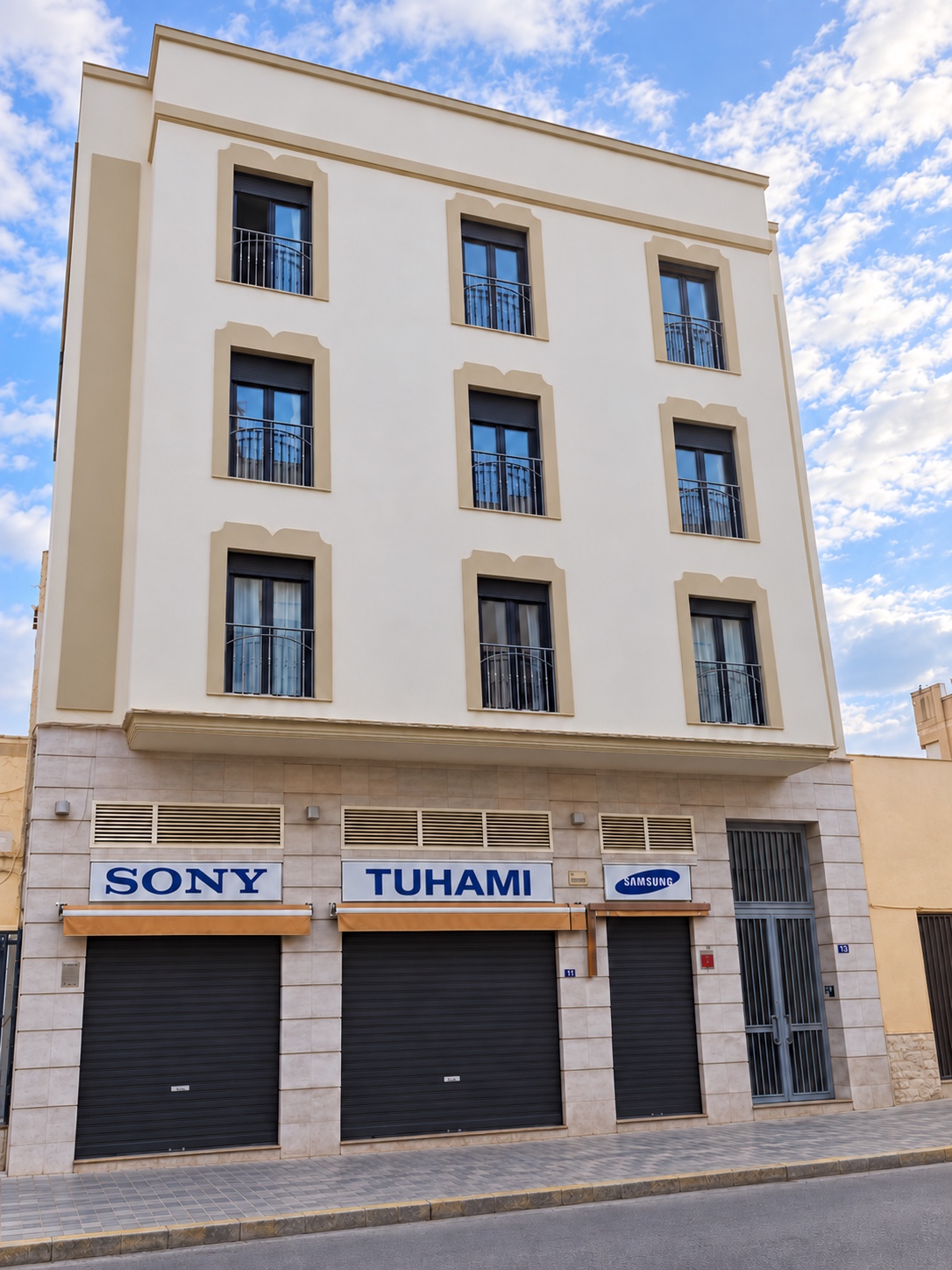 Vista frontal despejada de Hostal Tuhami en Melilla, con sus balcones y los rótulos de la planta baja