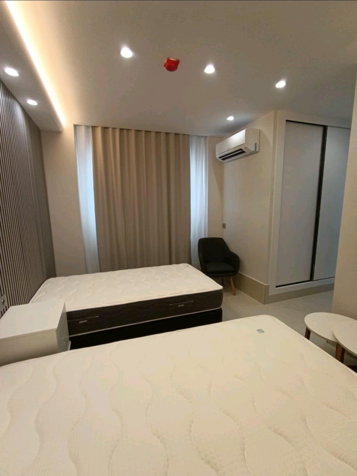 Interior de una habitación con dos camas, armario, cortinas y aire acondicionado